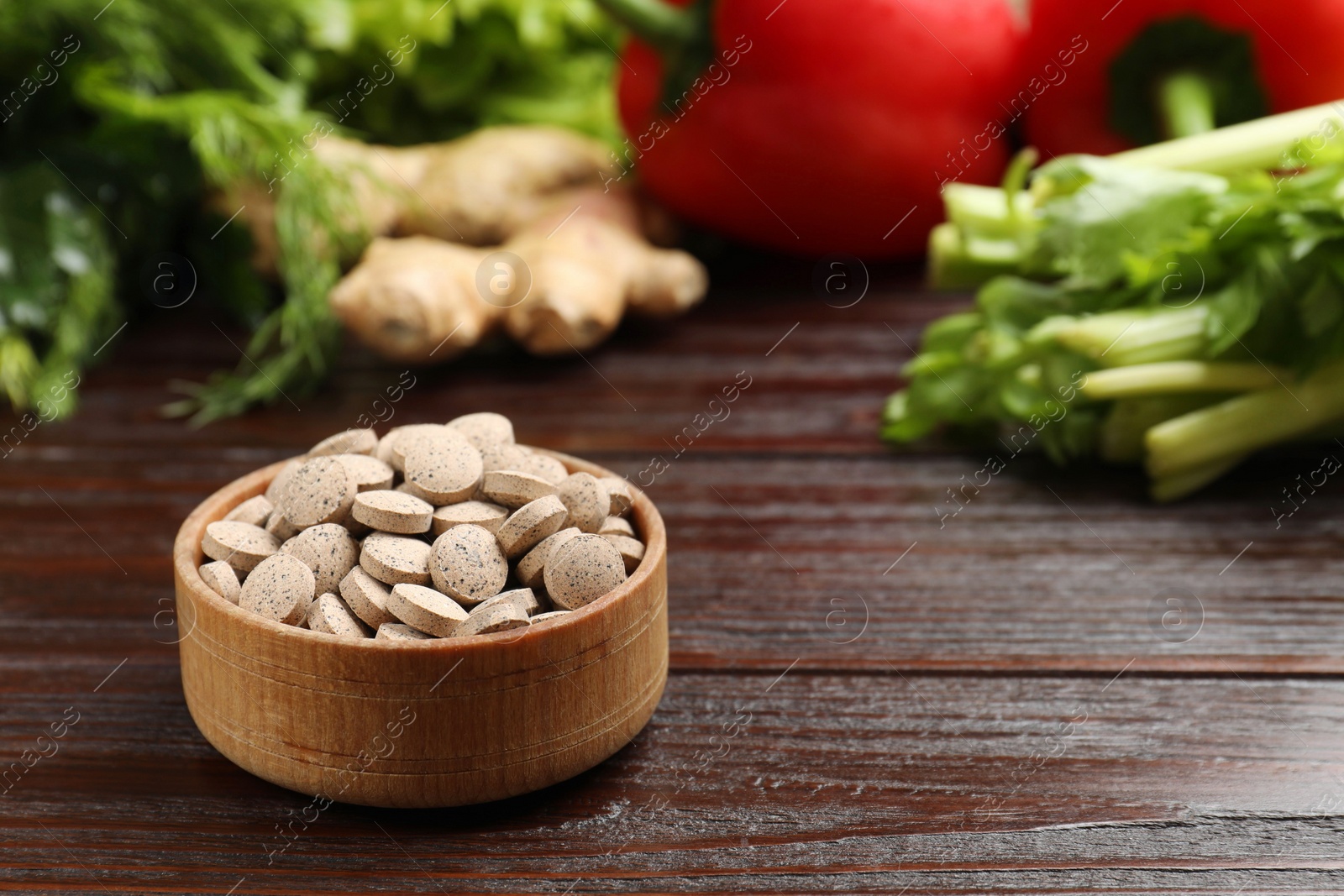 Photo of Dietary supplements. Pills in bowl and food products on wooden table, space for text