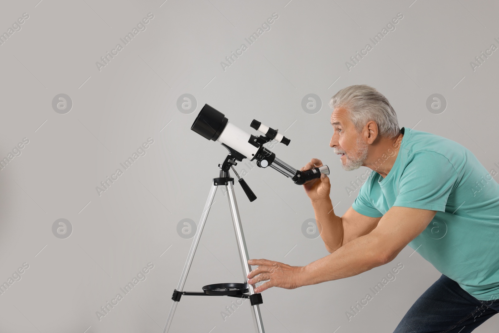 Photo of Senior astronomer with telescope on grey background. Space for text