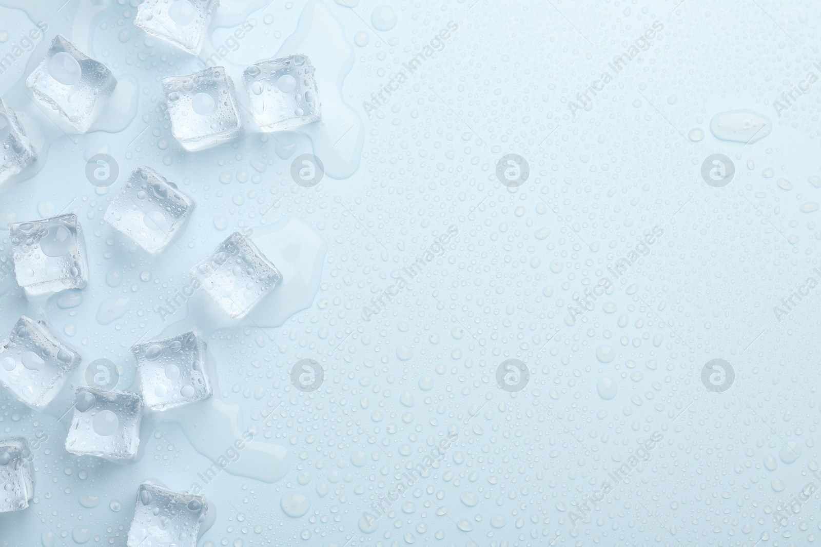 Photo of Crystal clear ice cubes on light blue background, flat lay. Space for text