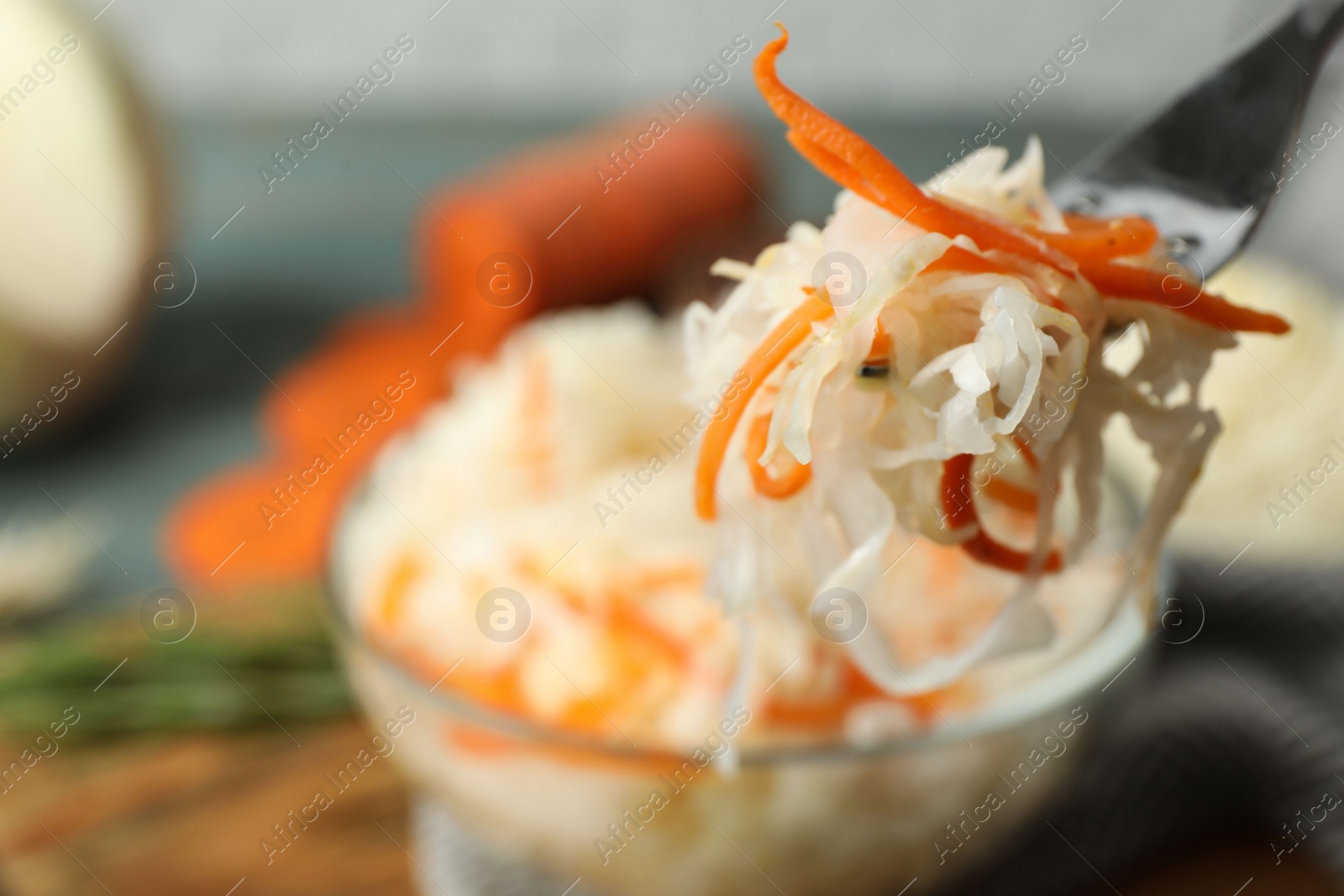 Photo of Fork with fermented cabbage on blurred background, closeup