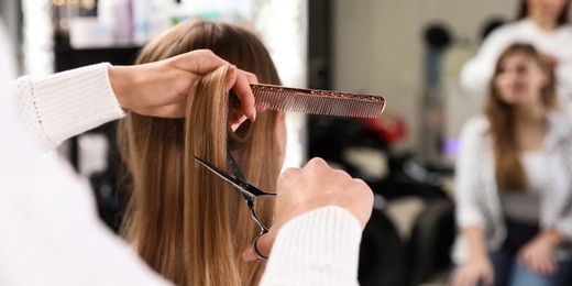 Image of Hairdresser making stylish haircut with professional scissors in salon, closeup. Banner design