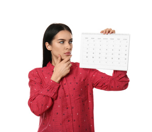Photo of Pensive young woman holding calendar with marked menstrual cycle days on white background