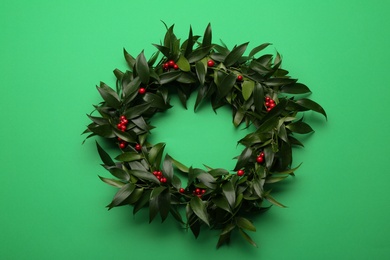 Photo of Beautiful handmade mistletoe wreath on green background. Traditional Christmas decor