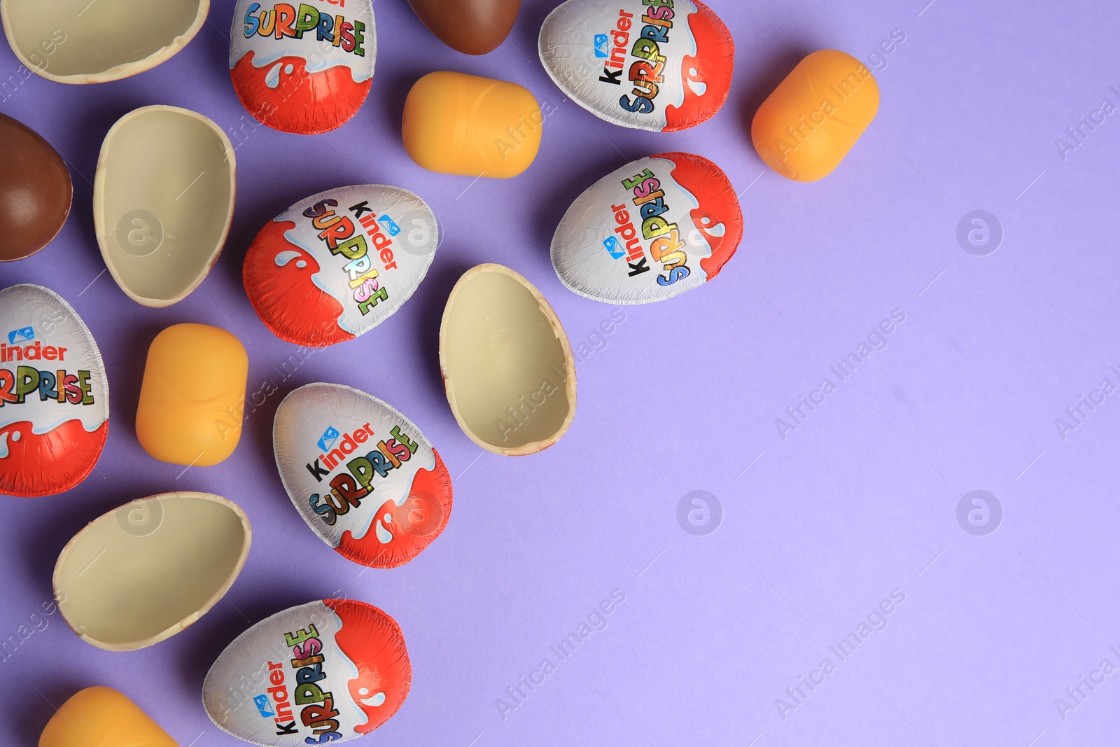 Photo of Sveti Vlas, Bulgaria - June 29, 2023: Kinder Surprise Eggs and plastic capsules on violet background, flat lay. Space for text