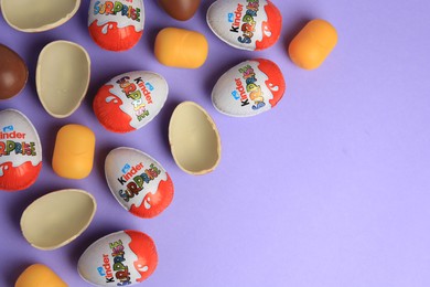 Sveti Vlas, Bulgaria - June 29, 2023: Kinder Surprise Eggs and plastic capsules on violet background, flat lay. Space for text