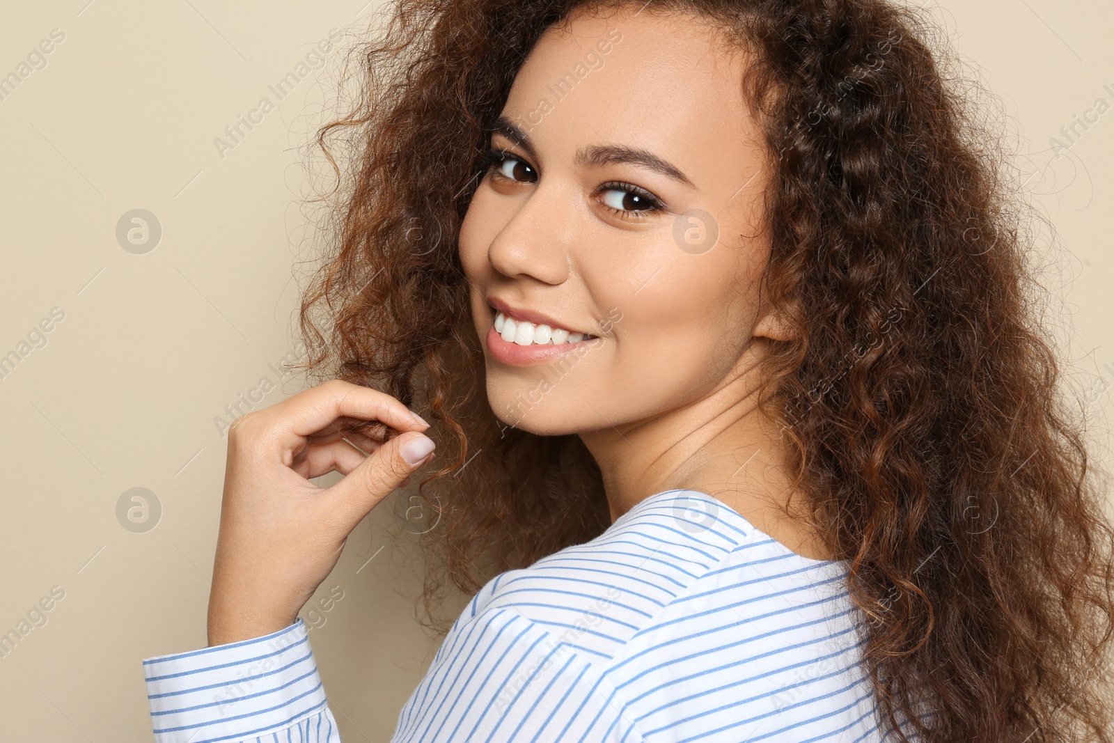 Photo of Young African-American woman with beautiful face on beige background