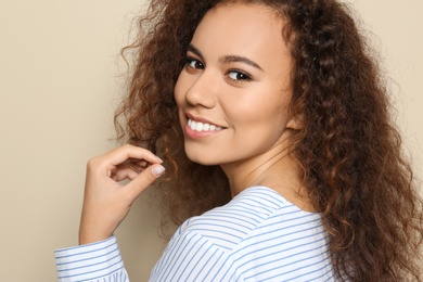 Photo of Young African-American woman with beautiful face on beige background