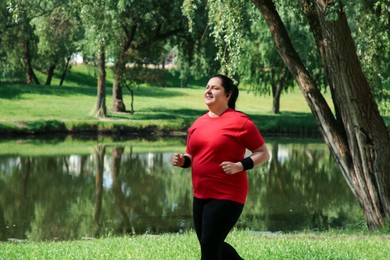 Photo of Overweight woman jogging near pond in park