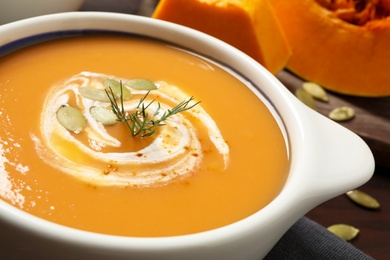 Photo of Tasty creamy pumpkin soup with dill and seeds in bowl on table, closeup