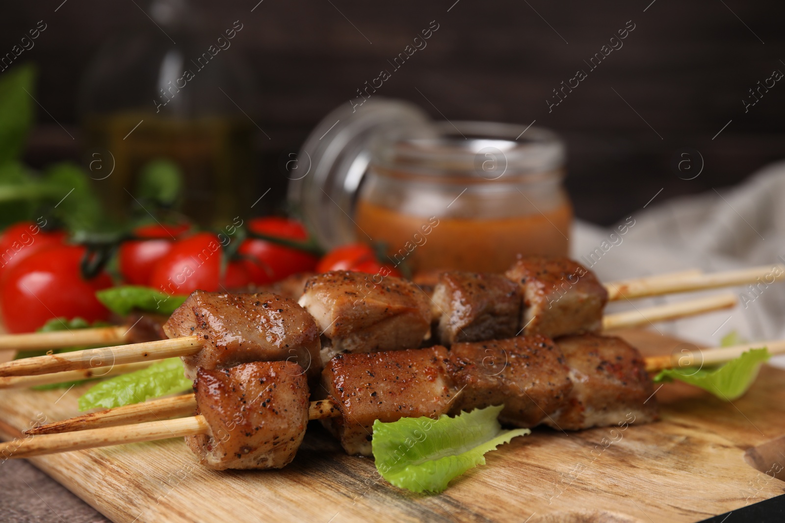 Photo of Tasty cooked marinated meat served with sauce and tomatoes on table, closeup