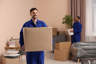 Photo of Male movers with cardboard boxes in new house