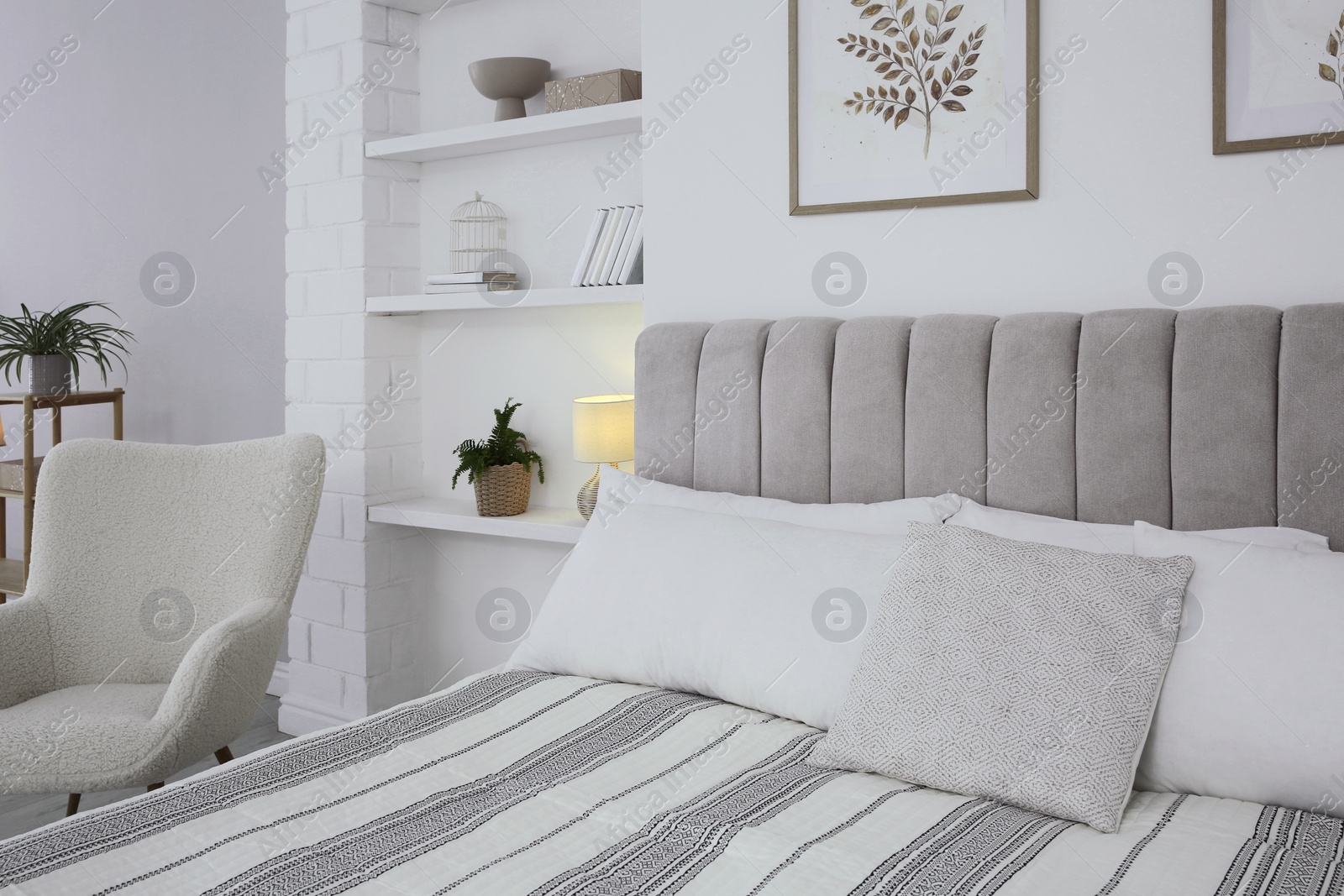 Photo of Large bed, armchair and houseplants in stylish bedroom