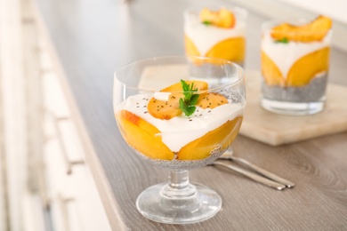 Photo of Tasty peach dessert with yogurt and chia seeds served on wooden table