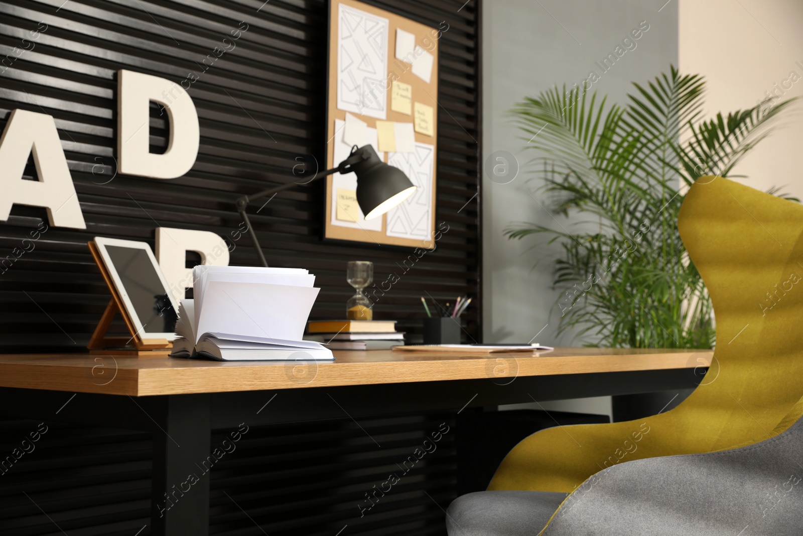 Photo of Comfortable workplace with wooden table and armchair