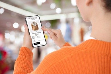 Image of Woman visiting shop to take ordered jacket indoors, closeup. Online store website on device screen