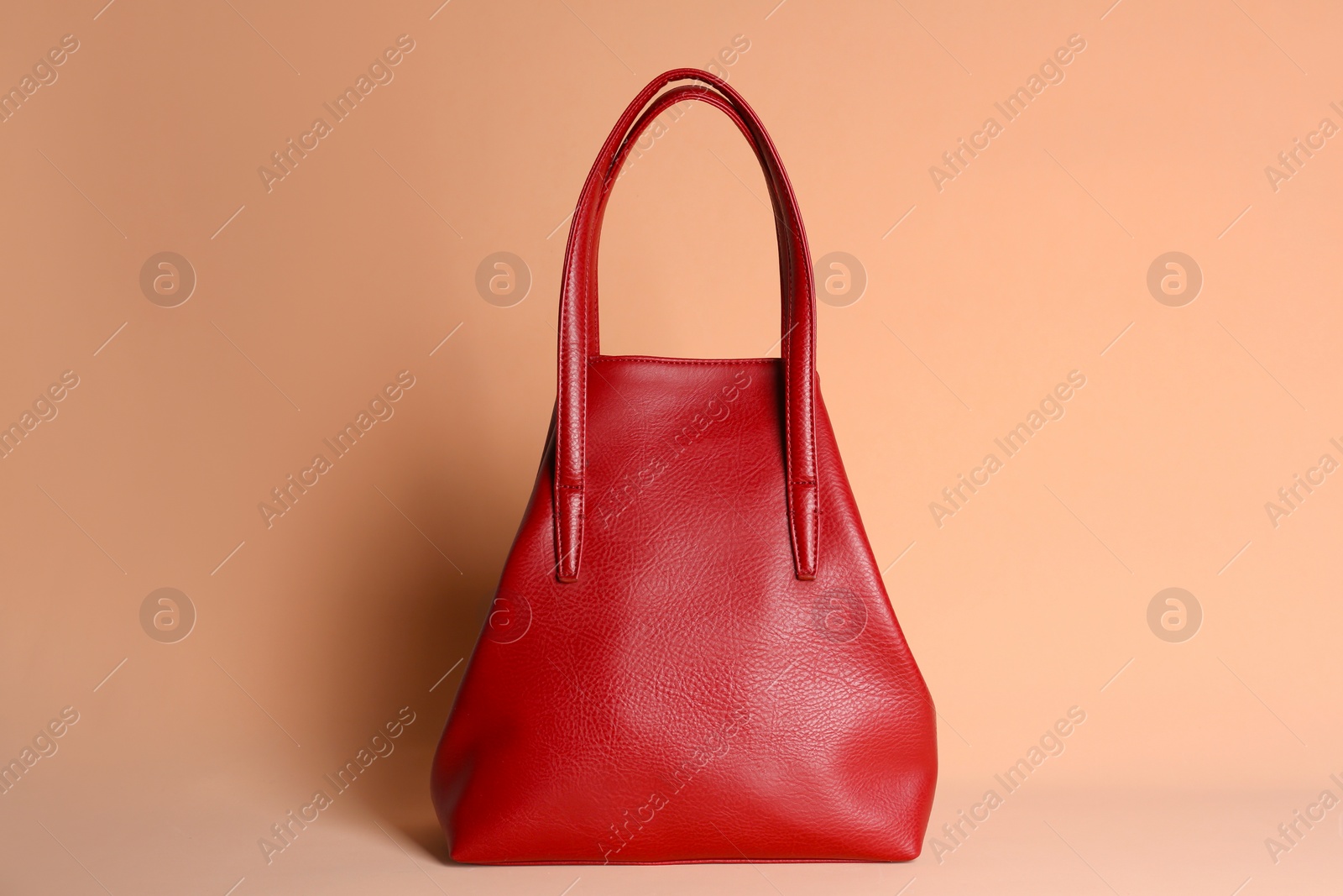 Photo of Red stylish woman's bag on pale pink background