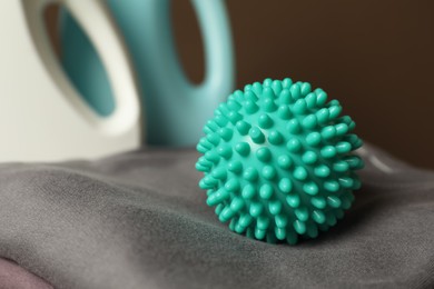 Photo of Turquoise dryer ball on clean clothing, closeup
