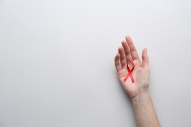Photo of Woman holding red awareness ribbon on white background, top view with space for text. World AIDS disease day