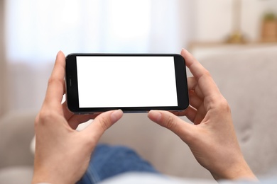 Photo of Woman holding smartphone with blank screen indoors, closeup of hands. Space for text