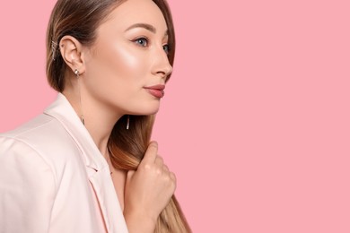 Photo of Young woman with lip and ear piercings on pink background, space for text