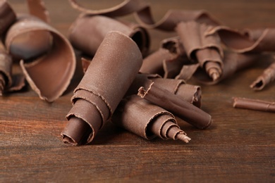 Photo of Chocolate curls for decor on wooden table, closeup