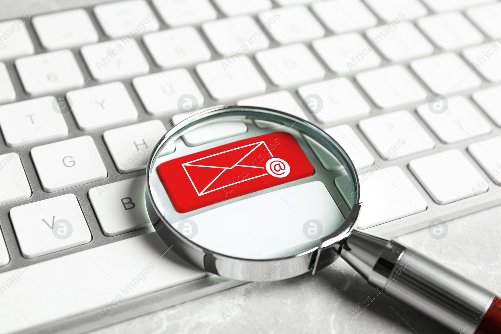 Image of Red button with illustration of envelope and email sign on computer keyboard, view through magnifying glass