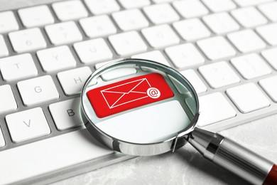 Red button with illustration of envelope and email sign on computer keyboard, view through magnifying glass