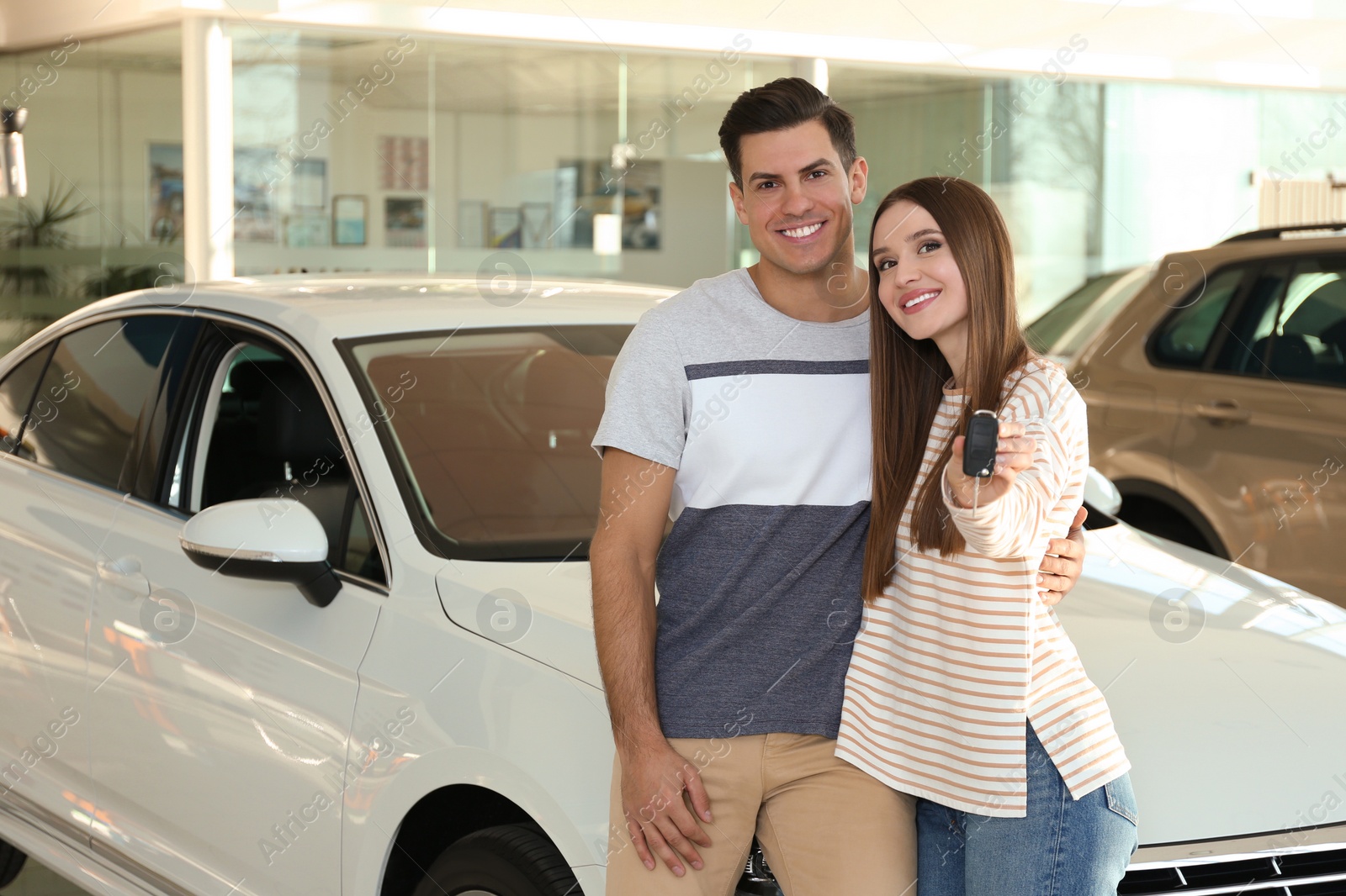 Photo of Happy couple with car key in modern auto dealership