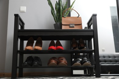 Photo of Shelving unit with stylish shoes and bag near grey wall in hallway, low angle view