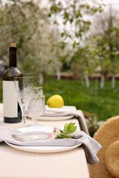 Photo of Stylish table setting with beautiful spring flowers, wine, plates and glasses in garden