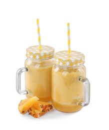 Tasty pineapple smoothie in mason jars and slices of fruit isolated on white