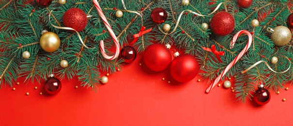 Photo of Fir tree branches with Christmas decoration on red background, flat lay. Space for text