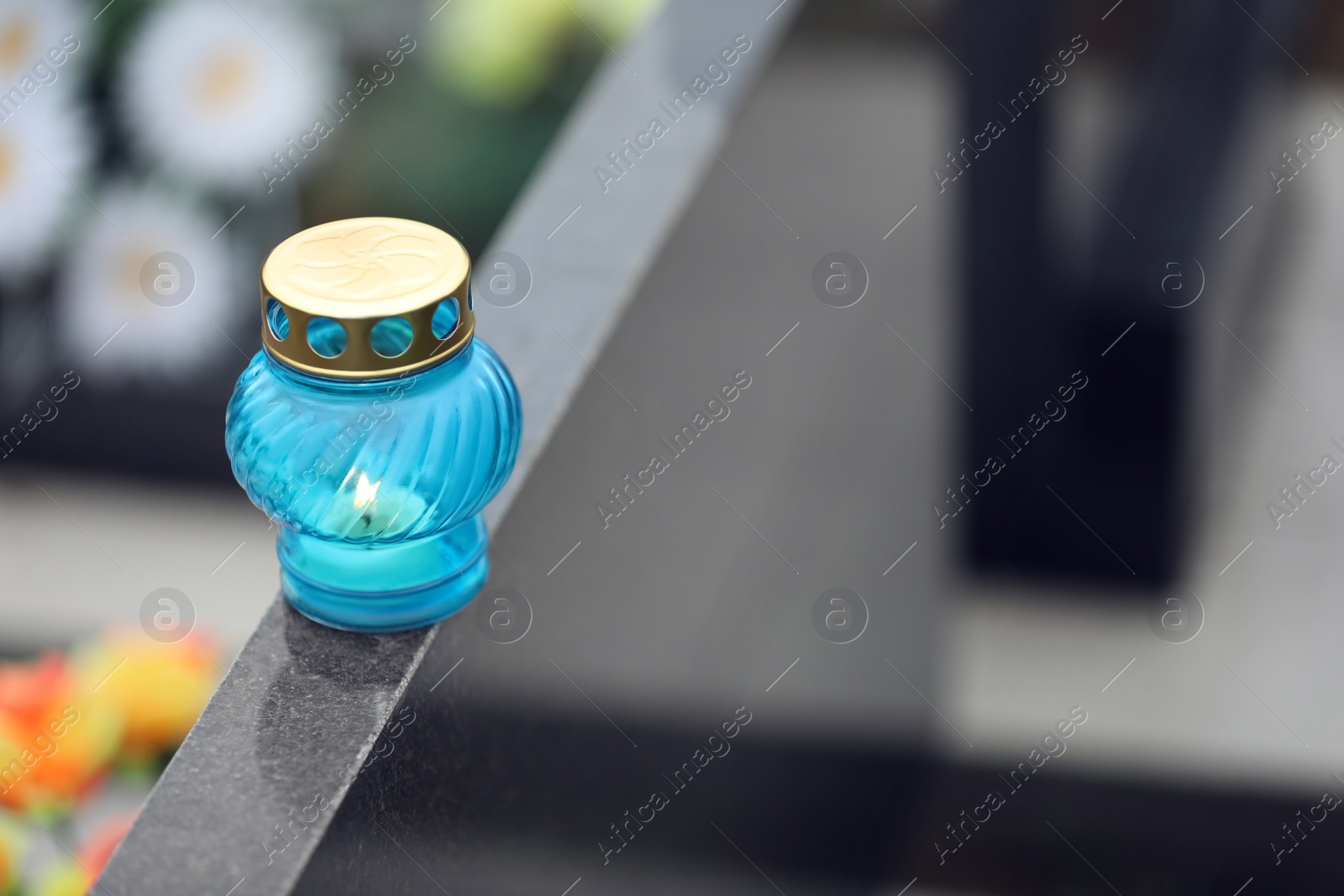 Photo of Candle on black granite tombstone outdoors, space for text. Funeral ceremony