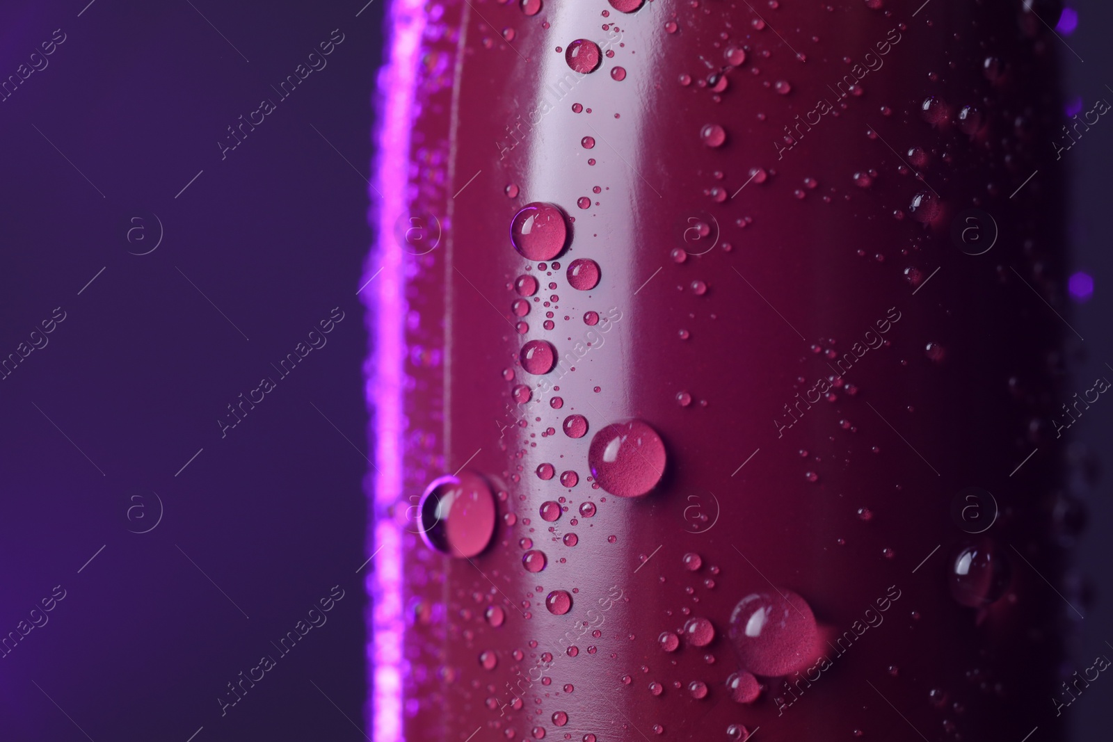 Photo of Lipstick with water drops on purple background, macro view. Space for text