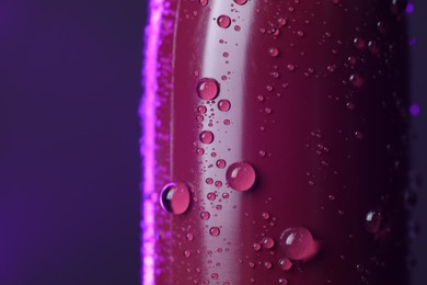 Photo of Lipstick with water drops on purple background, macro view. Space for text