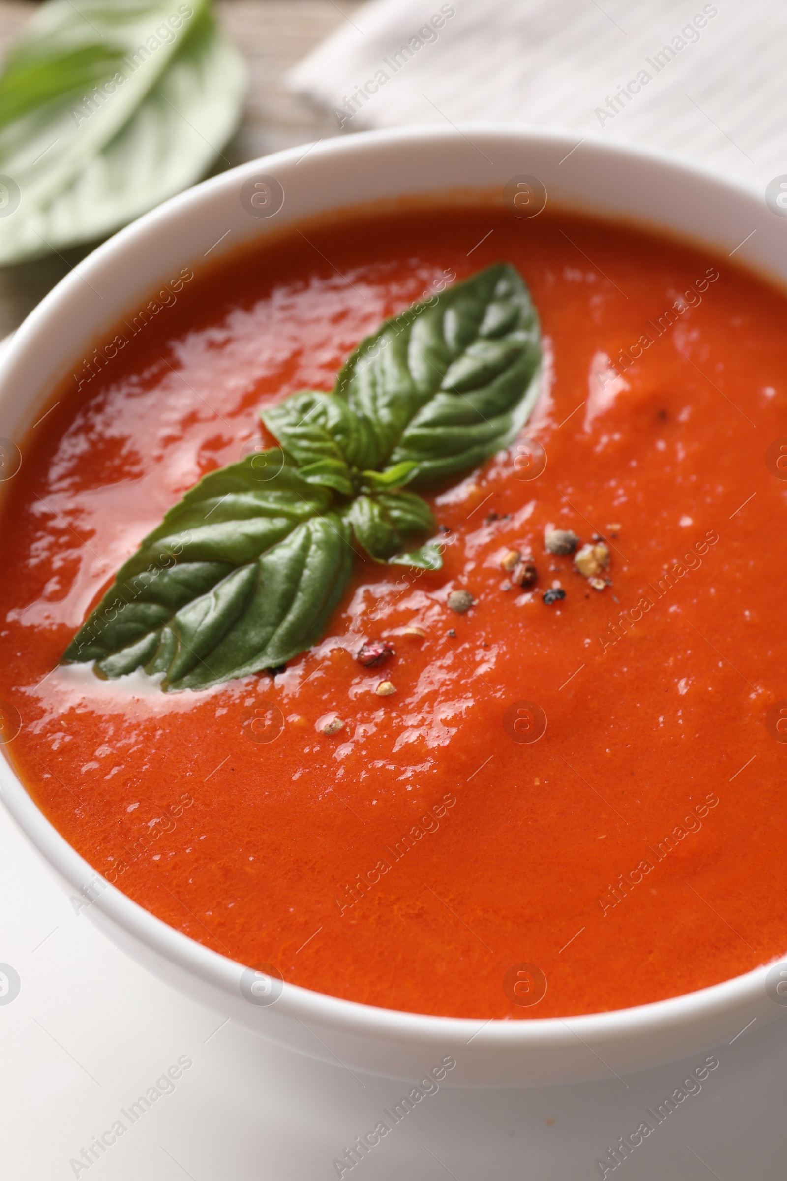 Photo of Delicious tomato soup with basil and spices on table, closeup