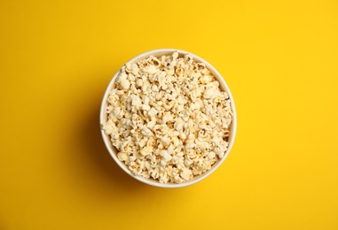 Paper bucket with tasty fresh popcorn on color background, top view