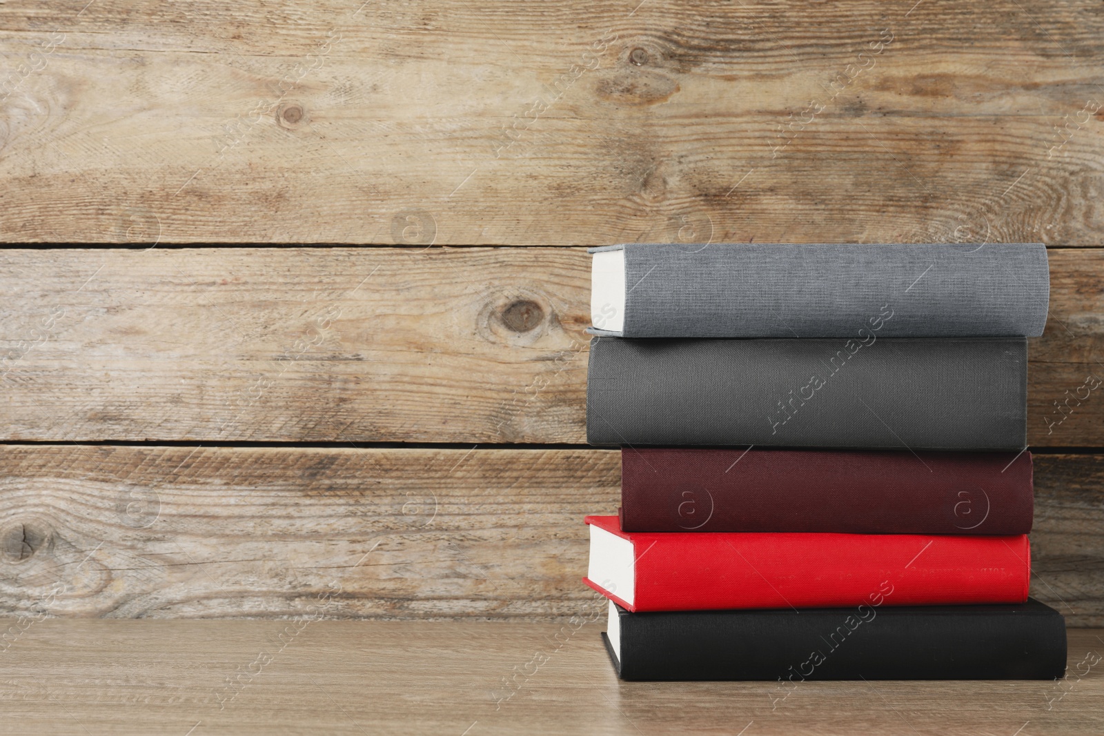 Photo of Stack of hardcover books on wooden table, space for text