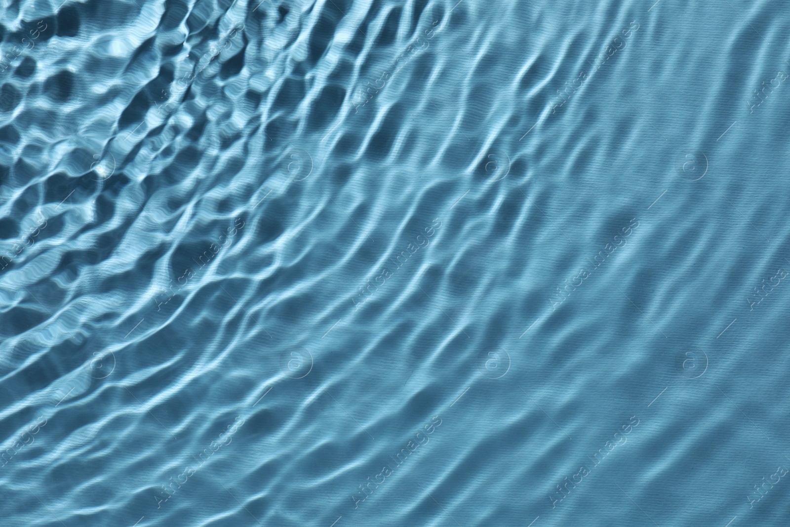 Photo of Rippled surface of clear water on light blue background, top view