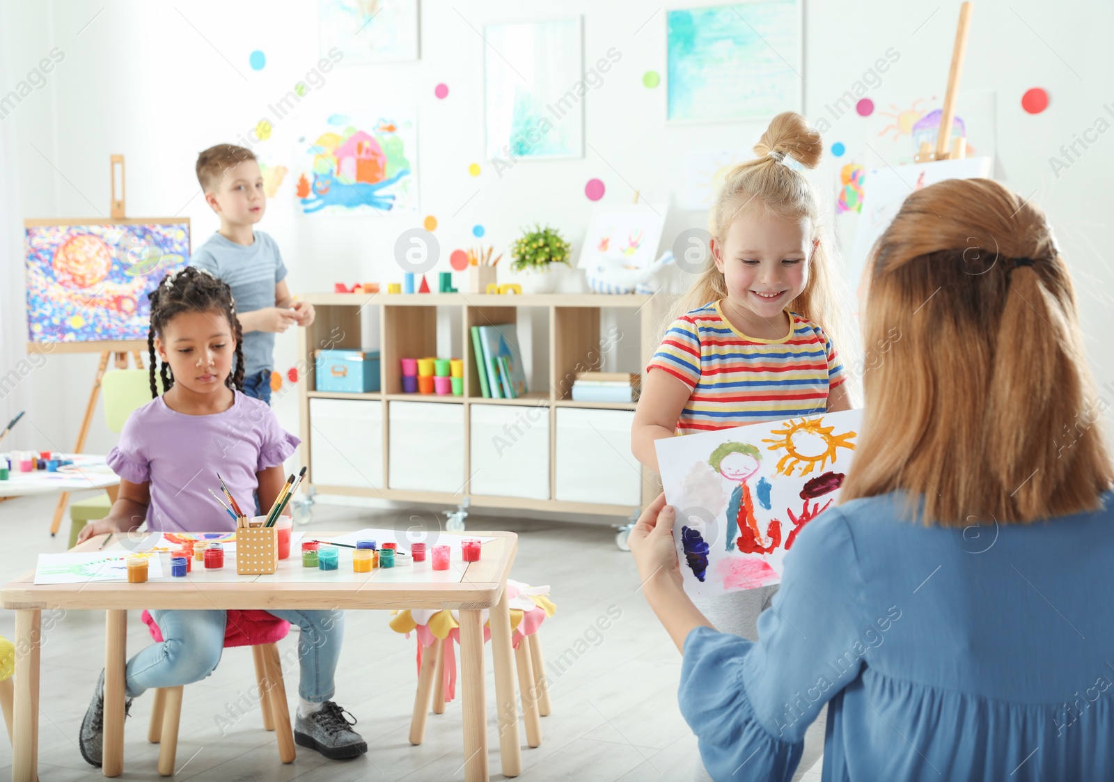 Photo of Children with female teacher at painting lesson indoors