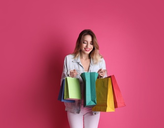 Beautiful young woman with shopping bags on color background