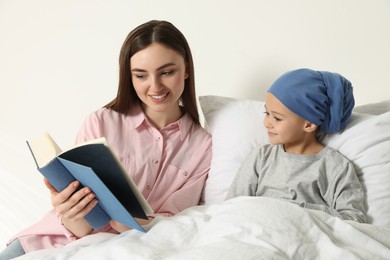 Photo of Childhood cancer. Mother and daughter reading book in hospital
