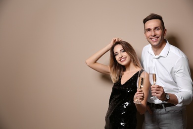 Photo of Happy couple with glasses of champagne on color background. Space for text