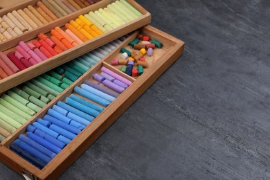 Photo of Colorful pastels in wooden trays on grey stone table, space for text. Drawing materials