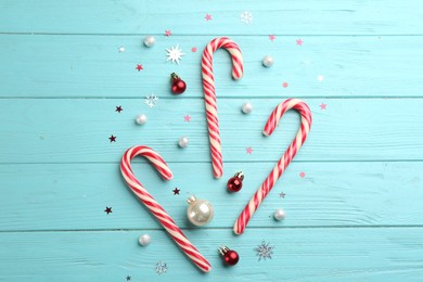Flat lay composition with candy canes and Christmas decor on cyan wooden table