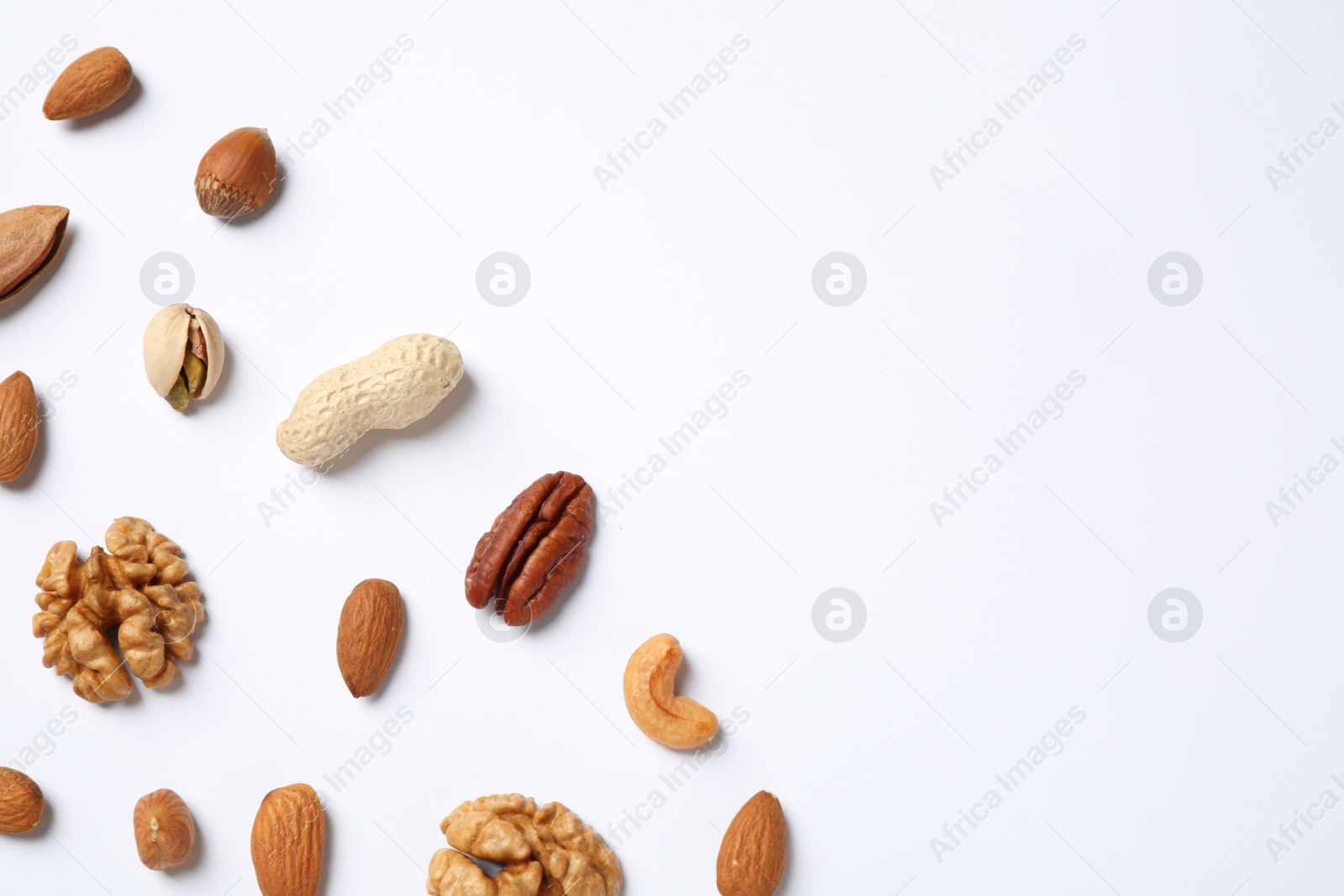 Photo of Different delicious nuts on white background, flat lay. Space for text