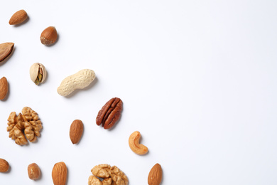 Different delicious nuts on white background, flat lay. Space for text