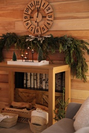 Christmas decor on console table near wooden wall with clock and garland. Interior design