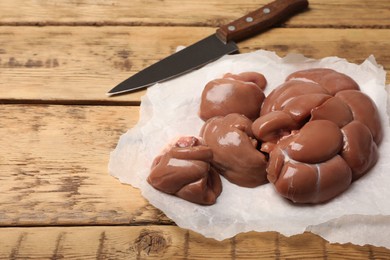 Photo of Fresh raw kidneys on wooden table, space for text