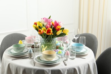 Photo of Easter celebration. Festive table setting with beautiful flowers and painted eggs